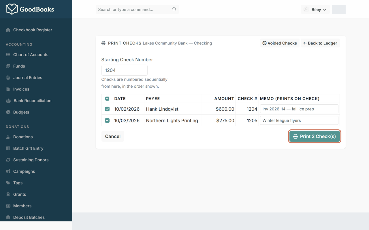 The Print Checks page listing two queued checks with their assigned numbers and a highlighted Print 2 Check(s) button
